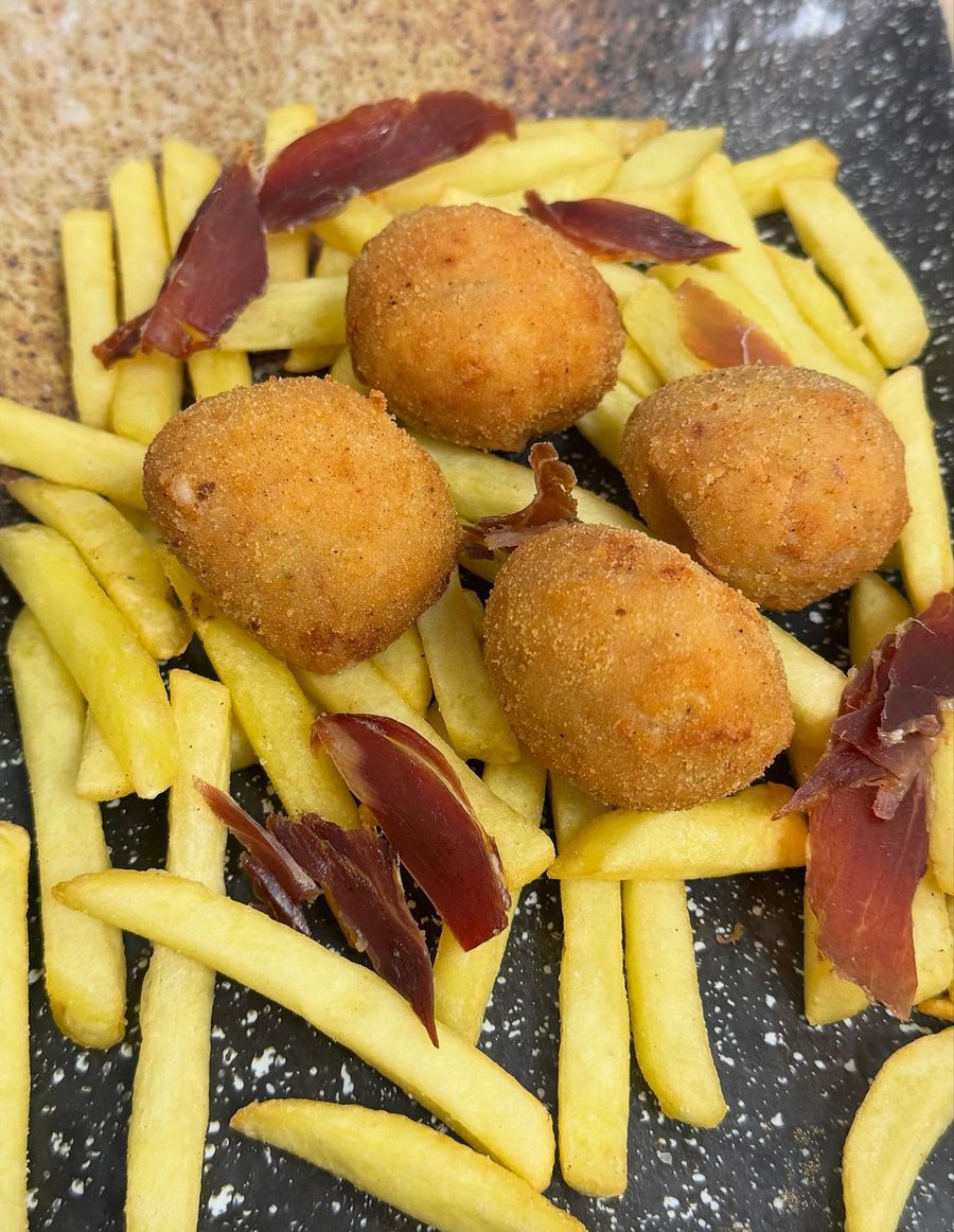 Croquetas caseras con patatas fritas y virutas de jamón